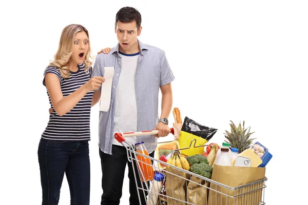 Casal chocado olhando para uma conta de compras — Fotografia de Stock