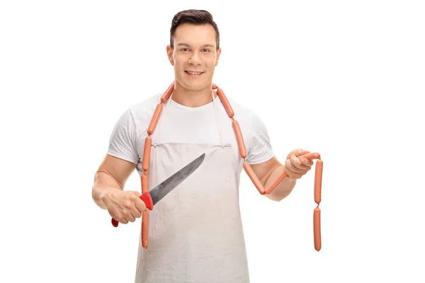 Carniceiro jovem com uma faca e salsichas cruas — Fotografia de Stock