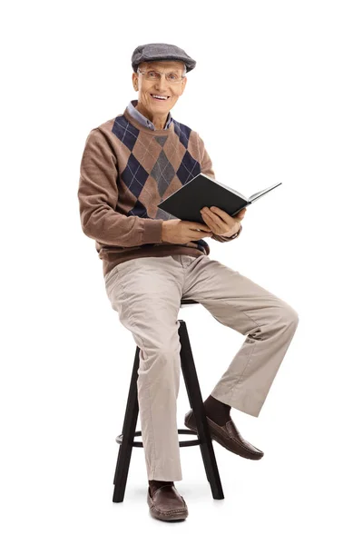 老人拿着一本书坐在椅子上 — 图库照片