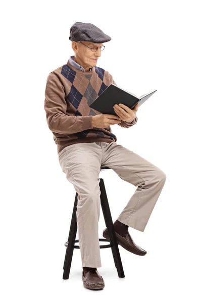 Senior sitting on a chair and reading a book — Stock Photo, Image