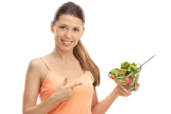 Menina feliz segurando uma salada e apontando — Fotografia de Stock