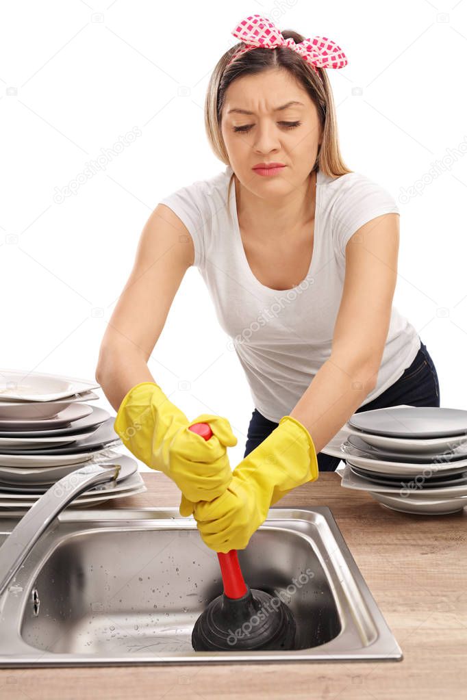 woman using a plunger to unclog a sink