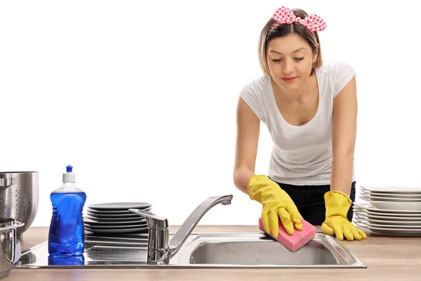Mujer joven limpiando un fregadero con una esponja —  Fotos de Stock