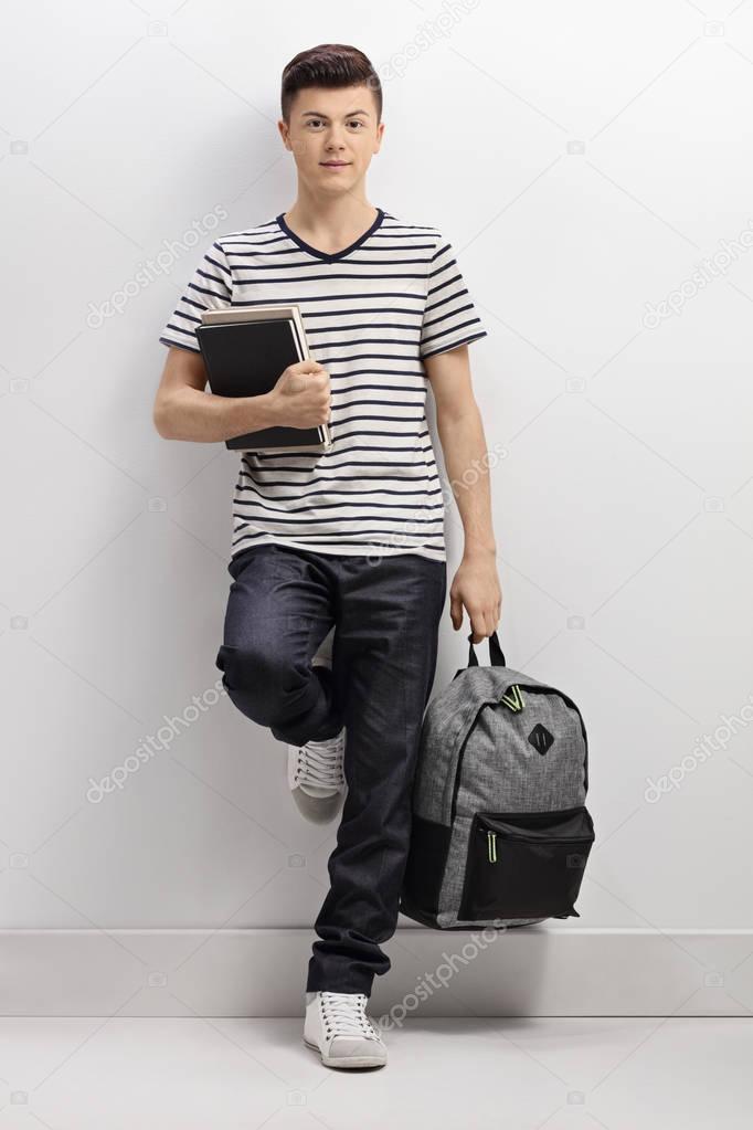 Teenage student leaning against a wall