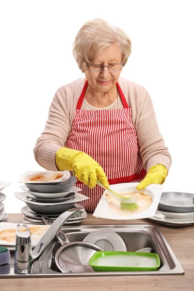 Mujer mayor limpiando los platos con un cepillo —  Fotos de Stock