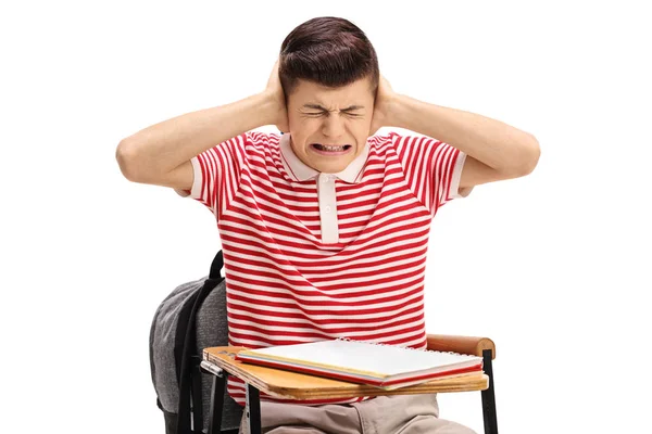 Teen student sitting in a chair and covering his ears — Stock Photo, Image