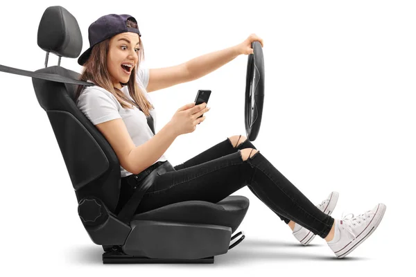 Teenage girl driving and looking at her phone — Stock Photo, Image