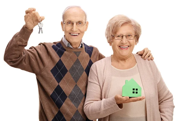 Радісні літні люди з парою ключів і модельним будинком — стокове фото