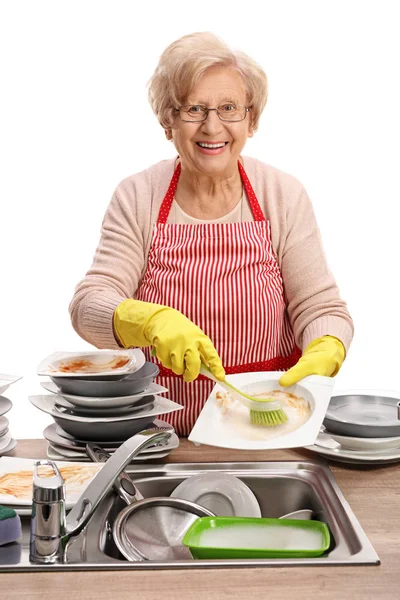 Зріла жінка чистить посуд пензлем — стокове фото