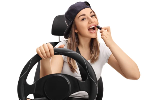 Teenage girl applying lipstick and driving — Stock Photo, Image