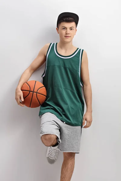 Teenager holding basketball and leaning on wall — Stock Photo, Image