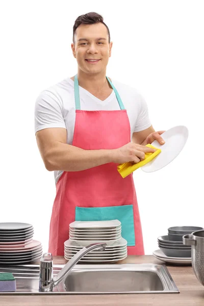 Young guy in an apron wiping dishes — Stock Photo, Image