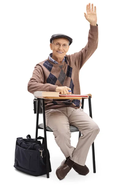 Anciano con la mano en alto sentado en la silla de la escuela —  Fotos de Stock