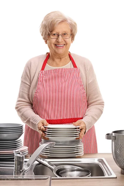 Mature woman with a stack of clean plates — Stock Photo, Image