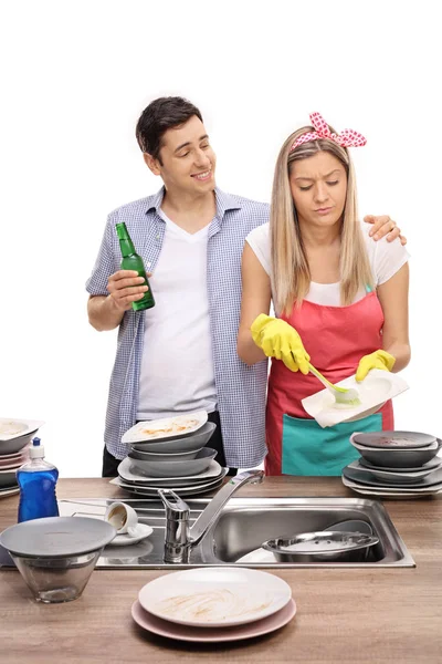 Мужчина с пивом обнимает жену, моет посуду — стоковое фото
