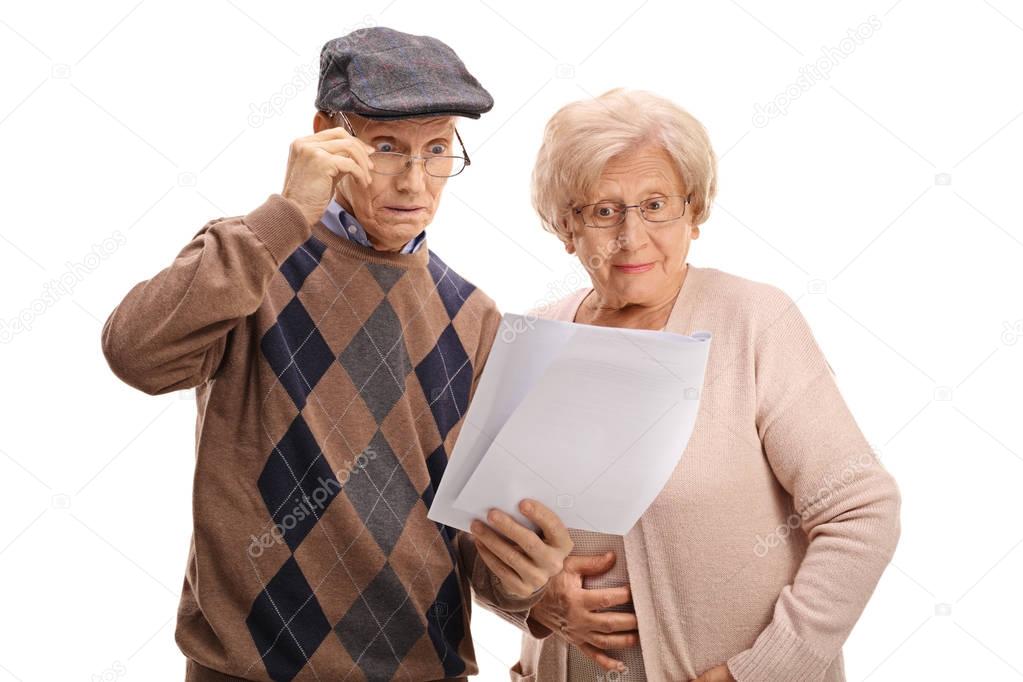 Surprised seniors looking at documents
