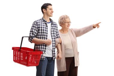 işaret eden yaşlı kadın ile bir alışveriş sepeti tutan adam