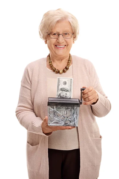 Пожилая женщина уничтожает долларовую банкноту в бумажном измельчителе — стоковое фото
