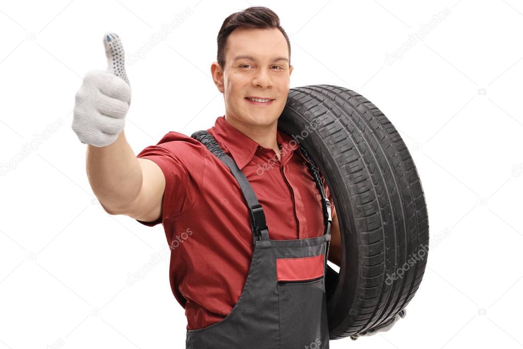 mechanic with a tire and making thumb up sign