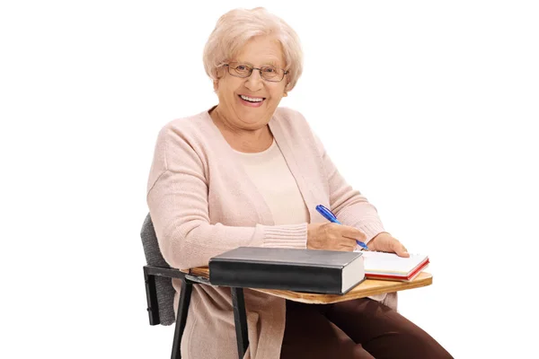 Étudiant âgé dans une chaise d'école prenant des notes — Photo