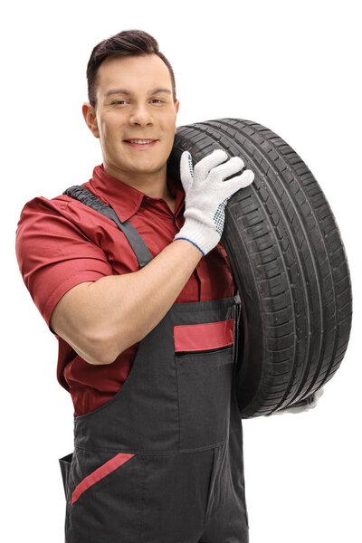 Young mechanic carrying a tire 