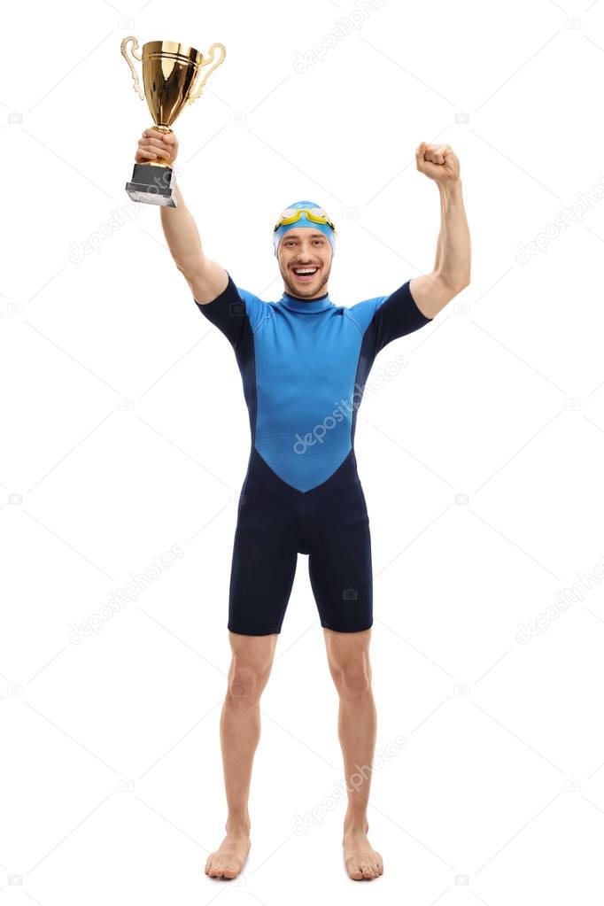 swimmer holding a gold trophy and gesturing happiness