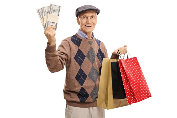 Пожилой человек с пачками денег и сумками для покупок — стоковое фото