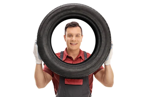 Mechaniker blickt durch einen Reifen in die Kamera — Stockfoto