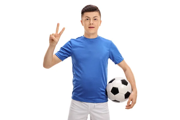 Joueur de football adolescent avec un ballon de football faisant un signe de victoire — Photo