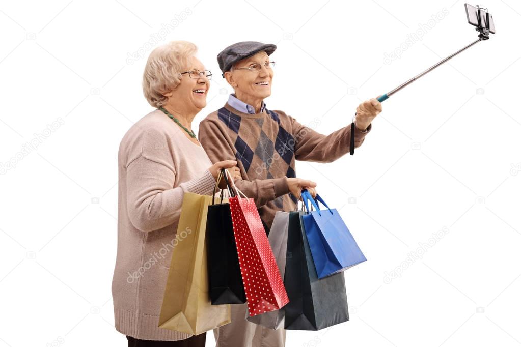 senior couple with shopping bags taking a selfie