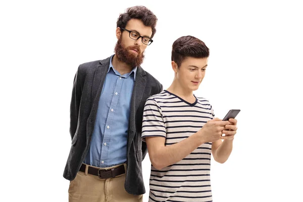 Обеспокоенный отец подглядывает за телефоном своего сына — стоковое фото