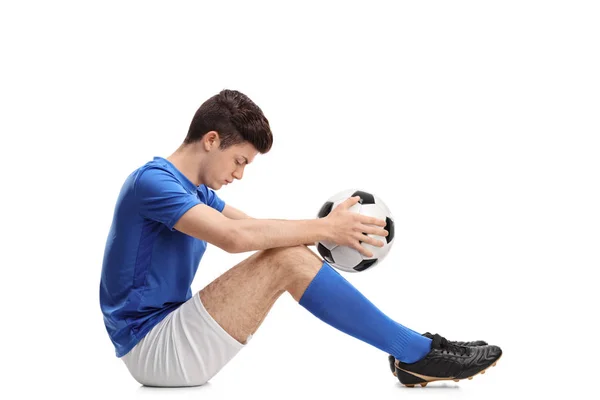 Depressed teenage football player sitting on the floor — Stock Photo, Image