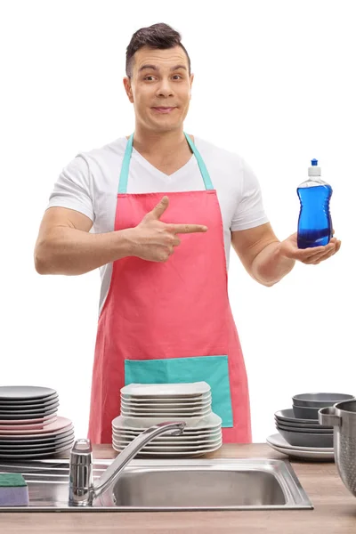 Muž za umyvadlo drží detergent a polohovací — Stock fotografie