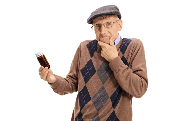 Confundido senior sosteniendo un frasco de pastillas — Foto de Stock