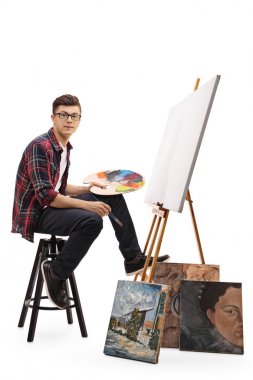 Boş bir tuval önünde oturan genç ressam