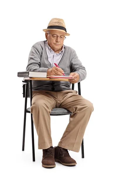 Sénior sentado em uma cadeira da escola e tomando notas — Fotografia de Stock