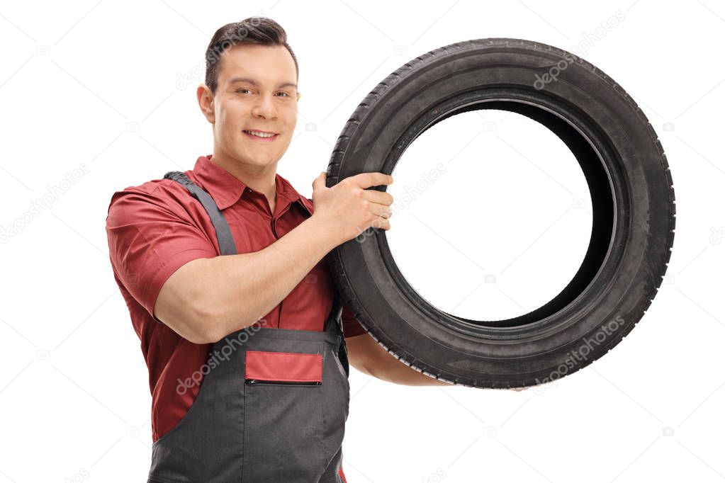 Young mechanic with a tire looking at the camera