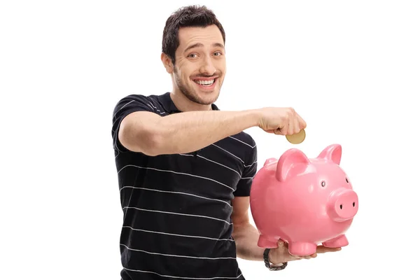 Lycklig man sätta ett mynt i en piggybank — Stockfoto