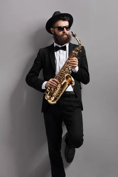 Saxofone jogador encostado a uma parede — Fotografia de Stock