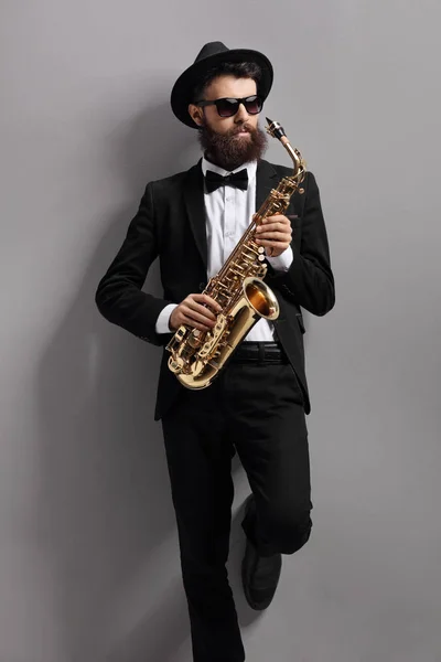 Saxophone player leaning against a wall — Stock Photo, Image