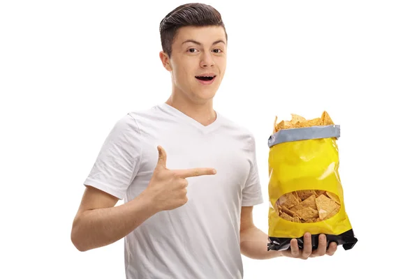 Nastolatek trzyma paczkę chipsów i wskazując — Zdjęcie stockowe