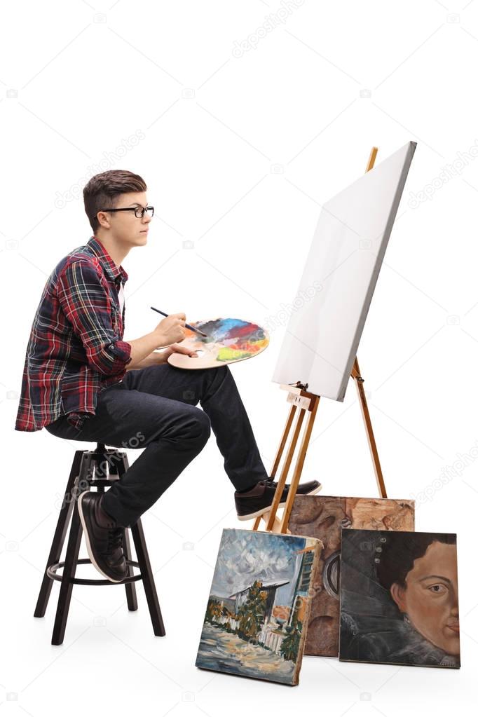 painter with paintbrush and palette looking at canvas