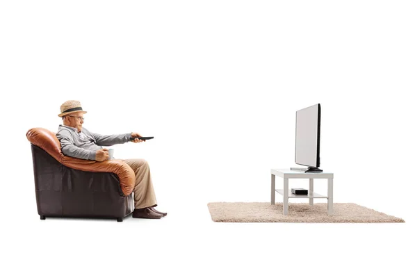 Człowiek siedzi w fotelu i oglądanie telewizji — Zdjęcie stockowe