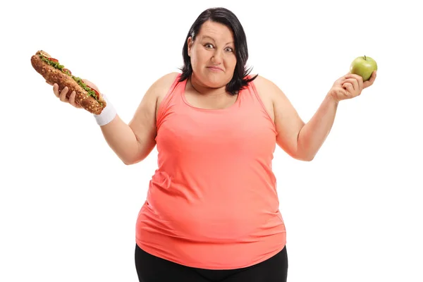 Mujer con sobrepeso sosteniendo un sándwich y una manzana —  Fotos de Stock