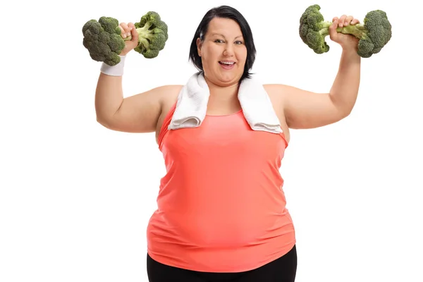 Överviktig kvinna tränar med broccoli hantlar — Stockfoto