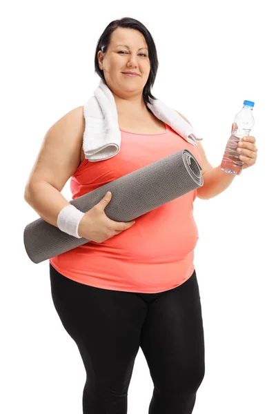 Mulher com excesso de peso segurando tapete de exercício e garrafa de água — Fotografia de Stock