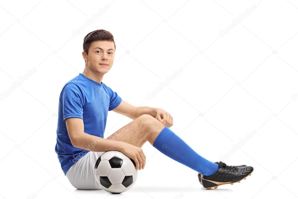 Teenage soccer player sitting on the floor