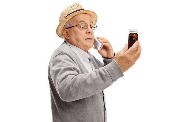 Bezorgd senior praten aan de telefoon en het houden van fles pillen — Stockfoto