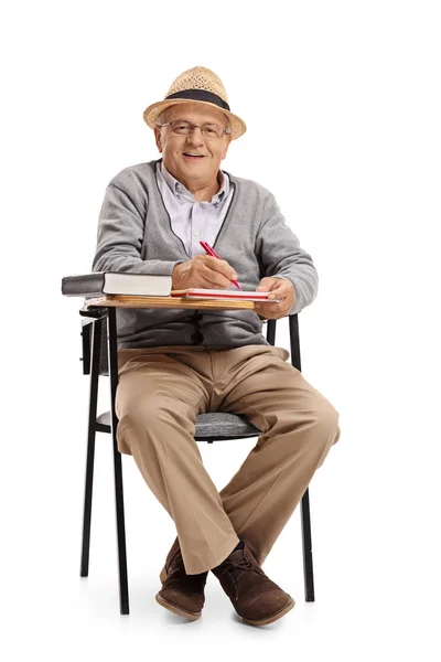 Hombre maduro en una silla de la escuela tomando notas — Foto de Stock
