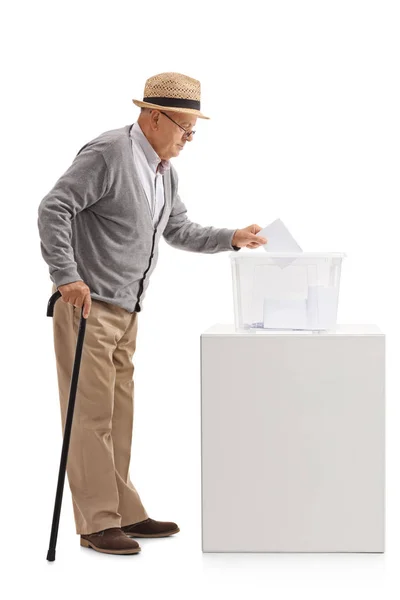 Пожилой человек кладет бюллетень в урну для голосования — стоковое фото